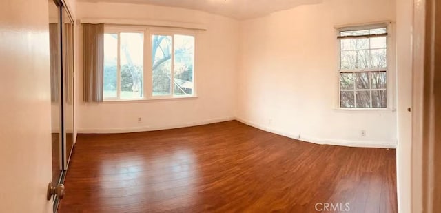 unfurnished room with dark wood-type flooring and baseboards