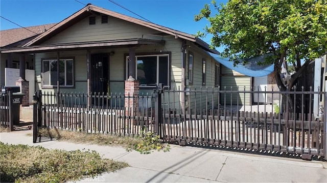 shotgun-style home featuring a porch and a fenced front yard