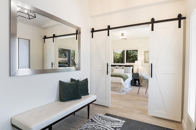 mudroom with a barn door, plenty of natural light, and wood finished floors