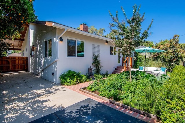 view of front of house featuring an outdoor hangout area, a chimney, fence, and stucco siding