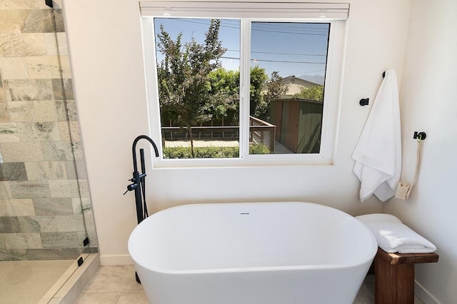 full bath featuring a stall shower, tile patterned floors, baseboards, and a soaking tub