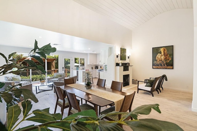 dining room with a fireplace, light wood-style floors, high vaulted ceiling, wooden ceiling, and baseboards