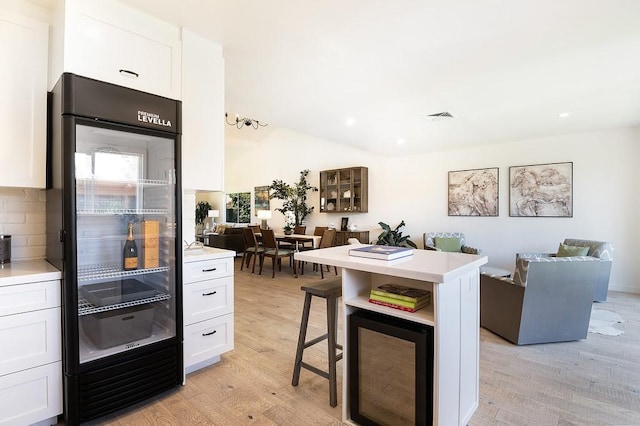 kitchen featuring open floor plan, a breakfast bar area, visible vents, and white cabinets