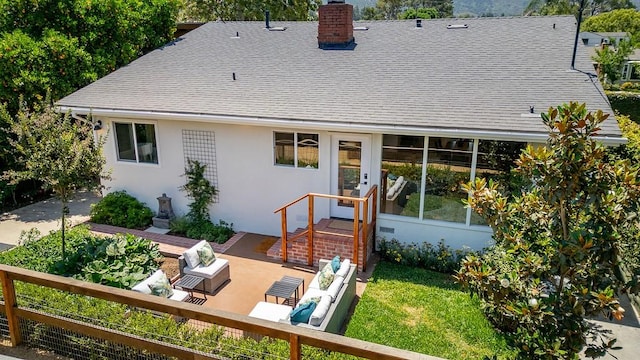 rear view of property with roof with shingles, a patio, a chimney, and stucco siding