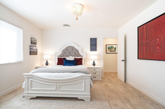 bedroom with light wood-type flooring, visible vents, and baseboards