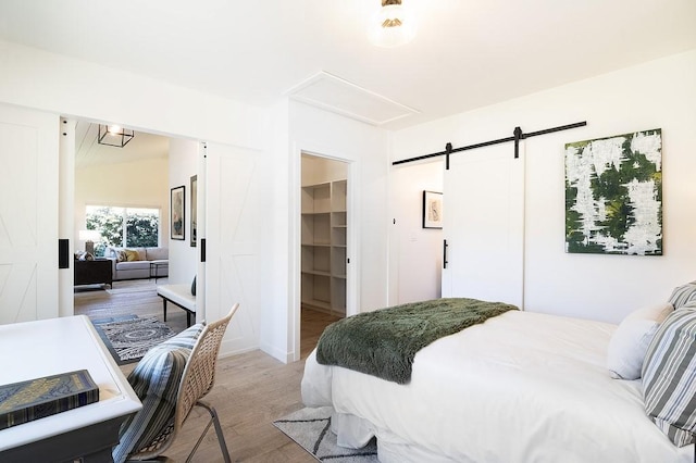 bedroom featuring wood finished floors, a barn door, a closet, and a walk in closet