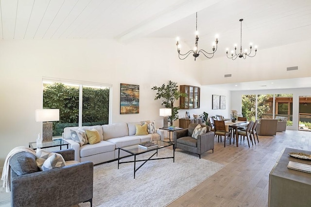 living area with a chandelier, a high ceiling, visible vents, light wood-type flooring, and beamed ceiling