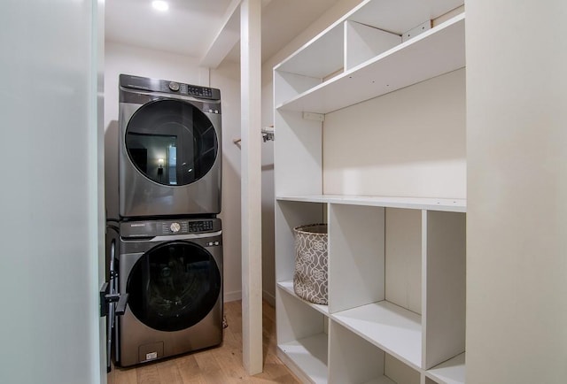 washroom with stacked washer / drying machine, laundry area, and light wood-style flooring