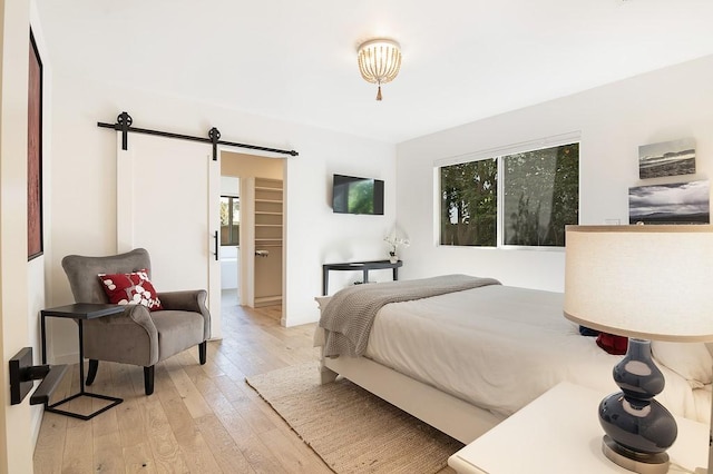 bedroom featuring light wood finished floors, a barn door, and multiple windows