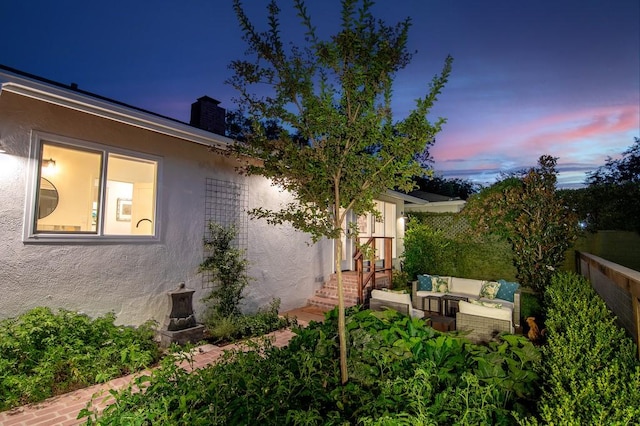 exterior space with an outdoor hangout area, a chimney, fence, and stucco siding