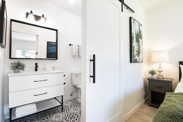 bathroom with toilet, wood finished floors, vanity, and baseboards