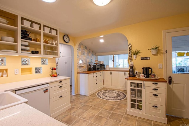 kitchen with lofted ceiling, white dishwasher, white cabinets, light countertops, and open shelves