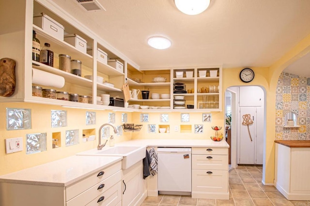 kitchen with light countertops, white dishwasher, a sink, and visible vents