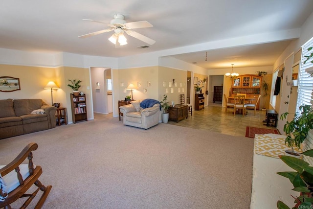 carpeted living room with tile patterned flooring, visible vents, and ceiling fan with notable chandelier