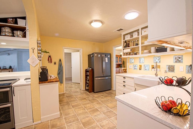 kitchen with light tile patterned floors, stainless steel appliances, open shelves, visible vents, and white cabinets