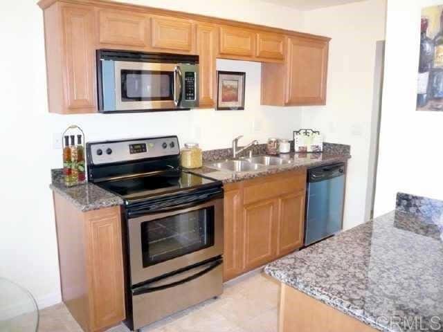 kitchen featuring stone countertops, appliances with stainless steel finishes, and a sink