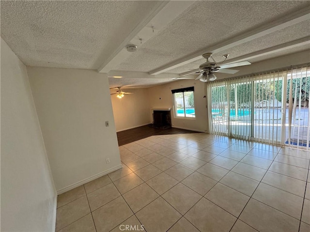 empty room featuring light tile patterned floors, a textured ceiling, a ceiling fan, and baseboards