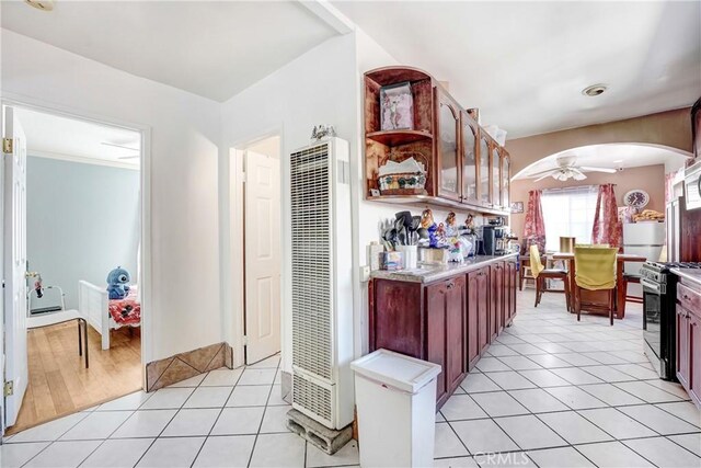 kitchen featuring light countertops, light tile patterned floors, a heating unit, and gas stove