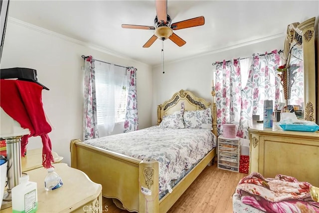 bedroom featuring light wood-type flooring, crown molding, and a ceiling fan
