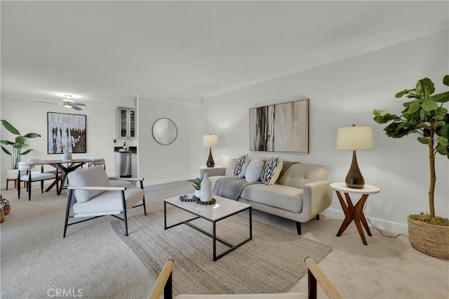 living area featuring ornamental molding, light carpet, ceiling fan, and baseboards