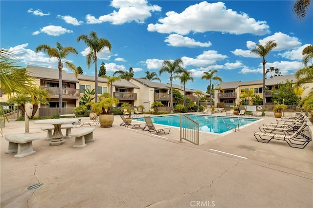 community pool with a patio, fence, and a residential view