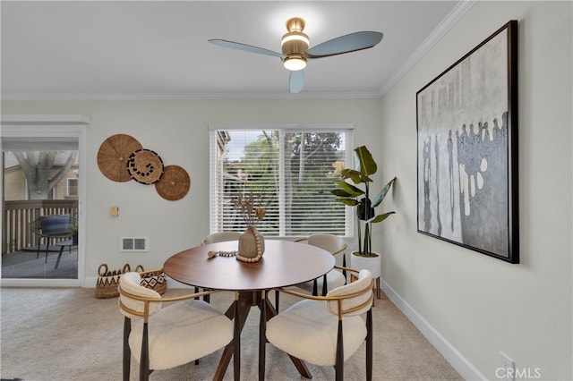 dining area featuring baseboards, visible vents, crown molding, and light colored carpet