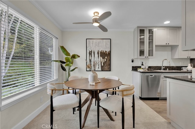 kitchen with baseboards, dishwasher, glass insert cabinets, crown molding, and a sink