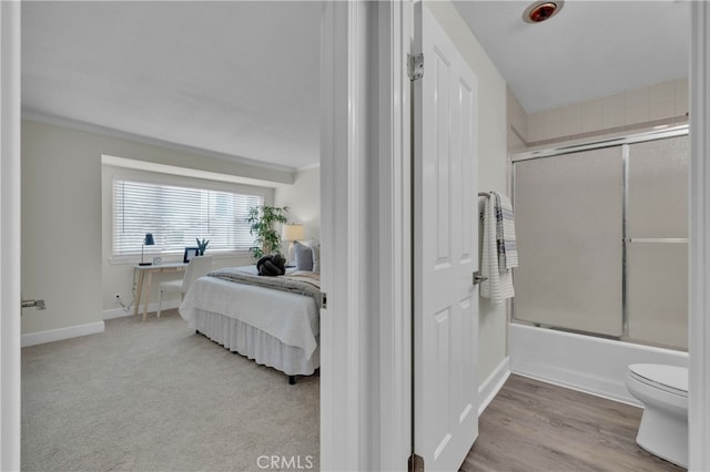 ensuite bathroom featuring baseboards, connected bathroom, toilet, combined bath / shower with glass door, and crown molding