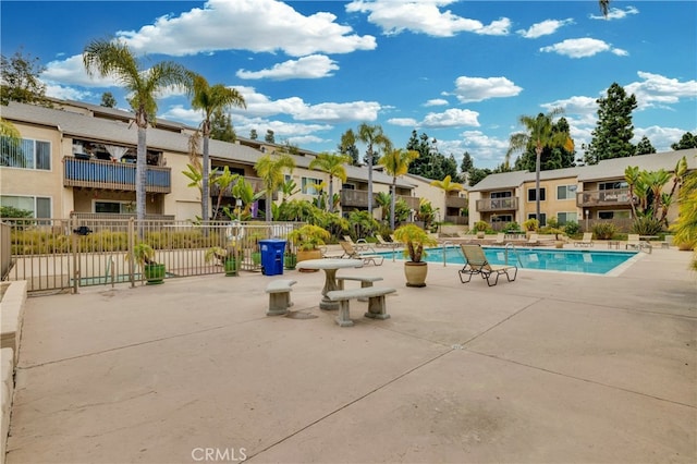 community pool with a residential view, a patio area, and fence