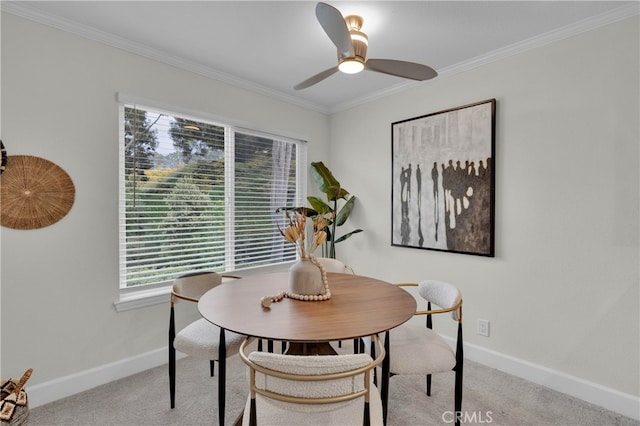 carpeted dining area with crown molding, baseboards, and ceiling fan