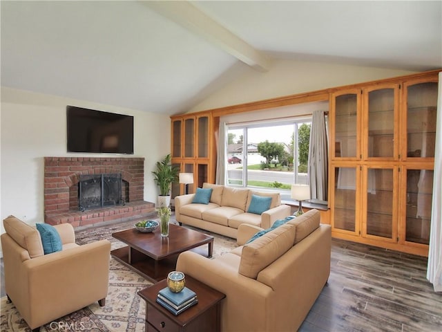 living area with lofted ceiling with beams, a brick fireplace, and wood finished floors