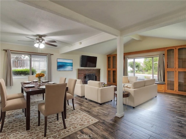 dining room featuring lofted ceiling with beams, a fireplace, a ceiling fan, and wood finished floors