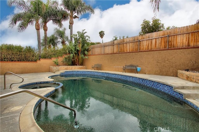 view of pool with a fenced backyard and a pool with connected hot tub