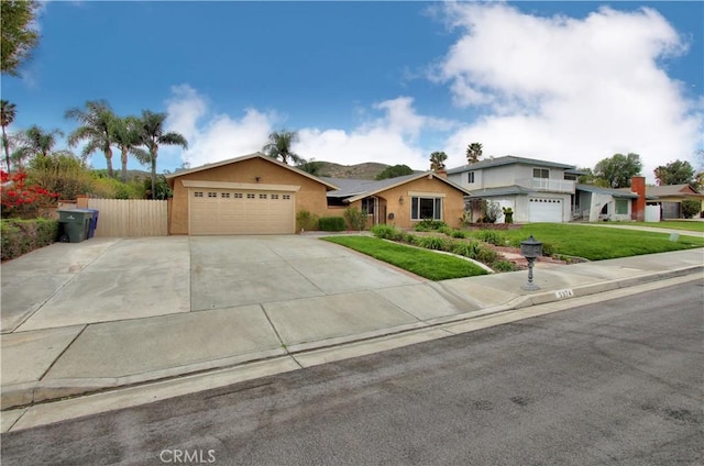 view of front of property with a garage, fence, concrete driveway, stucco siding, and a front yard