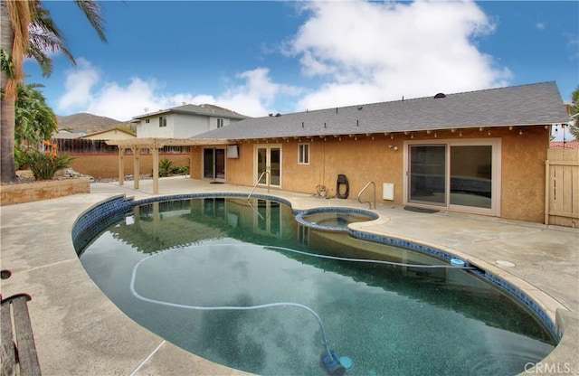 view of pool with a pool with connected hot tub, a patio, and fence