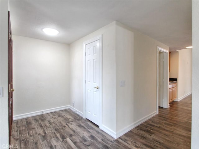 hall featuring dark wood-style floors and baseboards