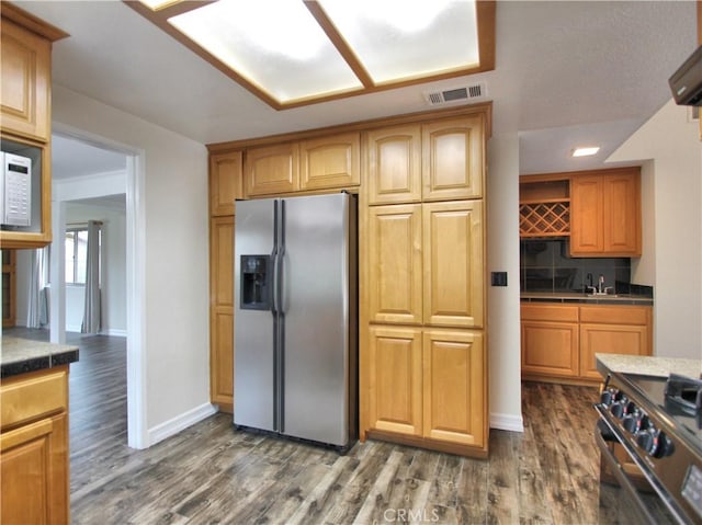 kitchen with visible vents, decorative backsplash, dark wood-style floors, stainless steel fridge, and gas range