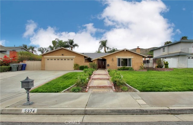 view of front facade featuring driveway, a garage, fence, and a front lawn