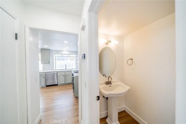 bathroom with wood finished floors, a sink, and baseboards