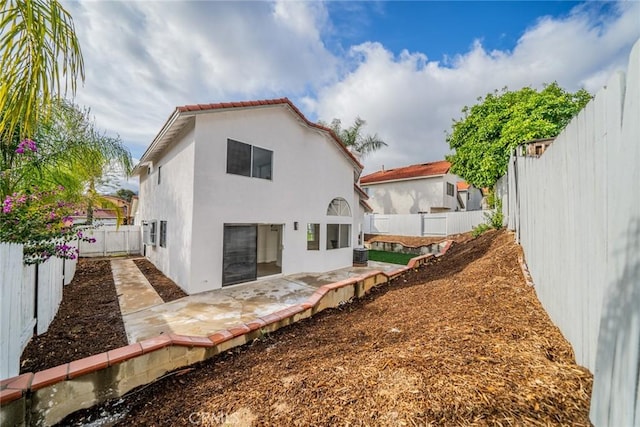 back of house with a patio area, a fenced backyard, central AC unit, and stucco siding