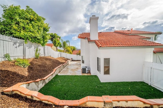 rear view of house with a patio area, a fenced backyard, a tile roof, and central AC unit