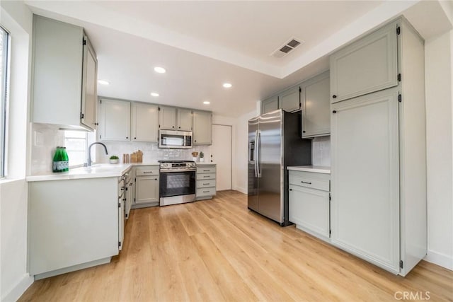 kitchen featuring stainless steel appliances, light countertops, a sink, and backsplash