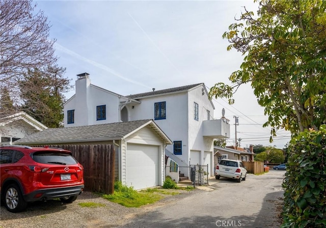 view of front of house with a garage, fence, a chimney, and stucco siding