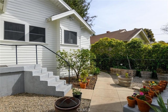 view of property exterior featuring an outdoor fire pit, a patio area, and fence