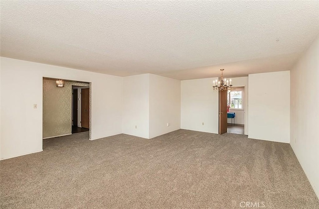 carpeted empty room with a notable chandelier and a textured ceiling