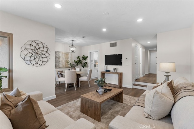 living area with recessed lighting, visible vents, an inviting chandelier, wood finished floors, and baseboards