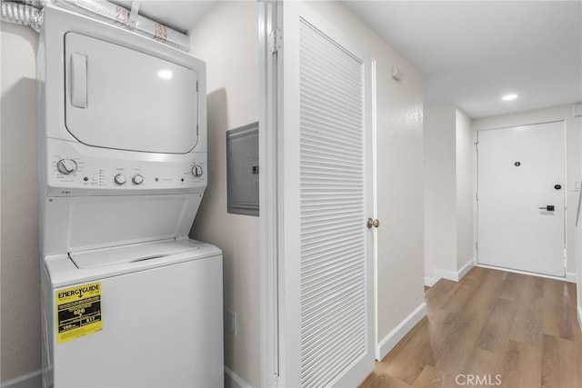 laundry area with stacked washer / drying machine, recessed lighting, wood finished floors, laundry area, and baseboards