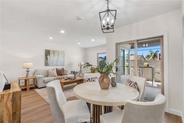 dining area with light wood-type flooring, baseboards, a chandelier, and recessed lighting