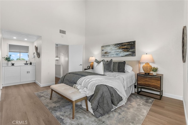 bedroom featuring baseboards, a sink, visible vents, and light wood-style floors