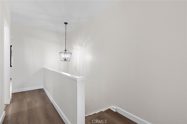 hall with dark wood-style flooring, an upstairs landing, and baseboards